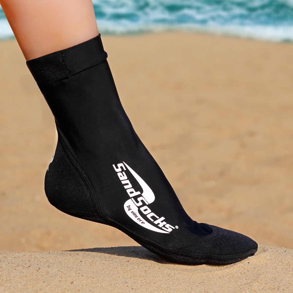 Schwarze, knöchelhohe SandSocks Classic am Fuß auf Sand
